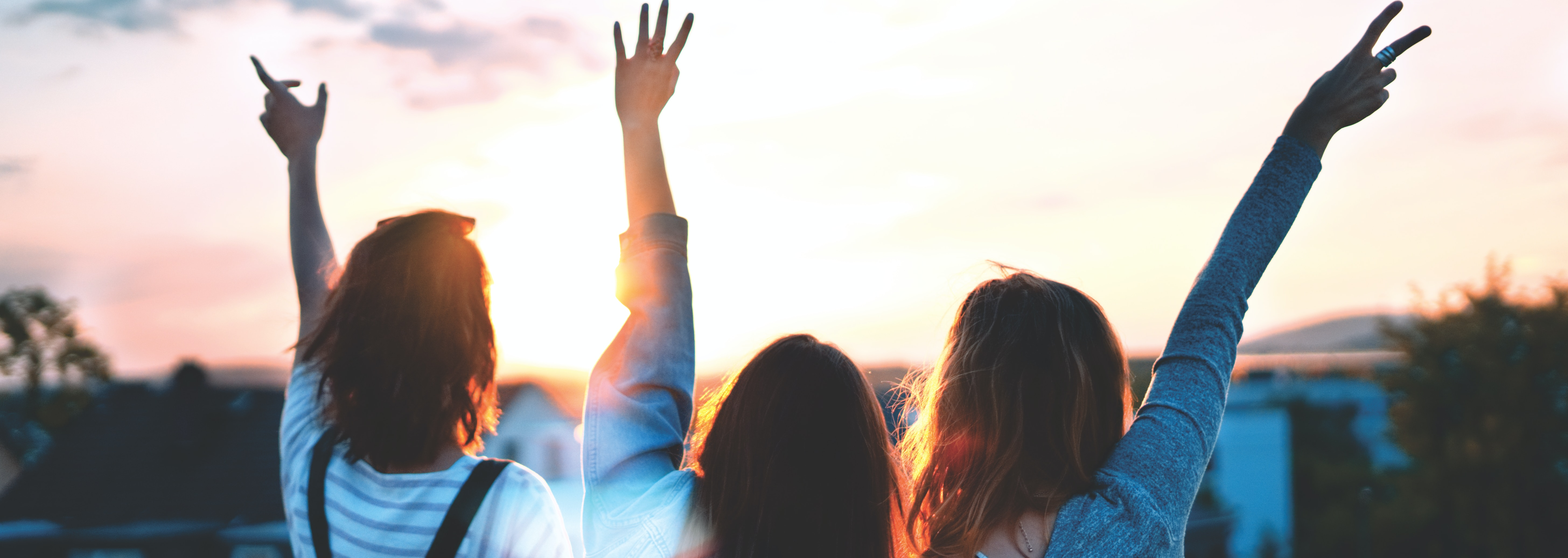 Three young people with hands in the air
